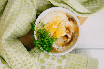 Indulge in a delectable baked dish topped with fresh dill and cheese, captured in a relaxing setting with soft textiles adding exquisite charm to the presentation.