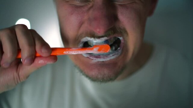 Un hombre se cepilla los dientes en el ba&ntilde;o.
Salud dental.
Higiene bucal.
Procedimientos matutinos.
Cepillo de dientes y pasta de dientes en las manos de una persona.