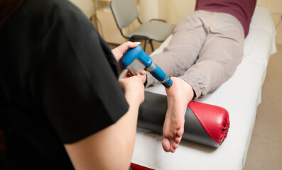 Physical therapy of foot with acoustic shock waves. Close up view of doctor performing shock wave...
