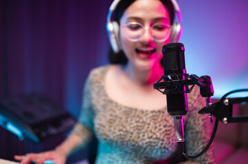 Asian teen girl playing guitar, composing music in home recording studio, LED lighting, at night...