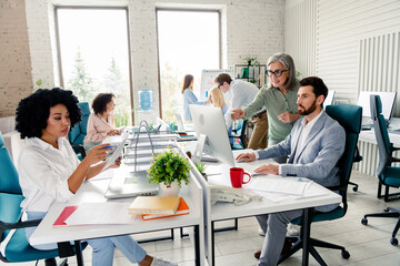 Collaborative team working in modern office interior with bright lighting during daytime,...