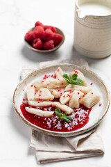 Lazy dumplings, vareniki with raspberry jam decorated with raspberry and mint leaves. Boiled cottage cheese homemade gnocchi.