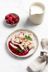 Lazy dumplings, vareniki with raspberry jam decorated with raspberry and mint leaves. Boiled cottage cheese homemade gnocchi.