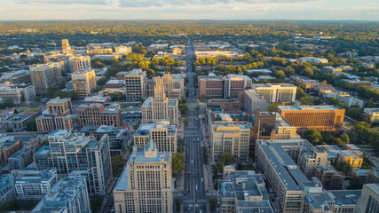 Aerial shot of a city with buildings, trees, and a long straight street in the daytime