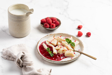 Lazy dumplings, vareniki with raspberry jam decorated with raspberry and mint leaves. Boiled cottage cheese homemade gnocchi.