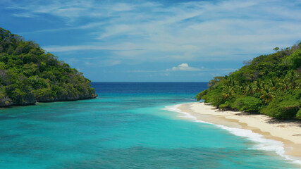 Fototapeta premium Tropical beach nestled between lush green hills and clear, turquoise sea water