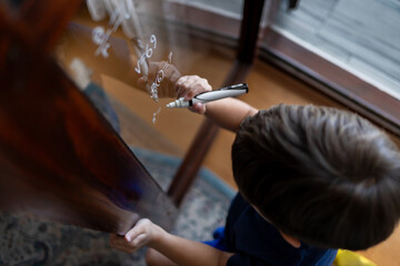 The child writes mathematical formulas on the glass with a marker.