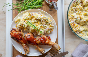 Deliciouse homemade chicken drumsticks with barbecue sauce and potato salad on a plate