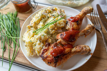 Deliciouse homemade chicken drumsticks with barbecue sauce and potato salad on a plate