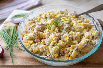 Healthy homemade potato salad with corn, pickles, red onions, a little mayonnaise and yogurt in a bowl. Without eggs