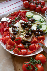 Oven baked feta cheese with marinated kalamata olives and vegetables on a plate. Delicous greek food
