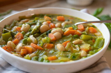 Spring vegetable soup with white beans on a plate fresh and homemade cooked