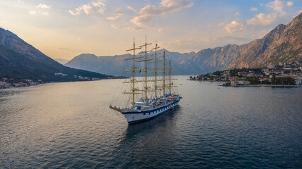 Sunset landscape of the Royal Clipper sailing ship in the Bay of Kotor in the sea between the mountains. Used cruise ship travel and holidays