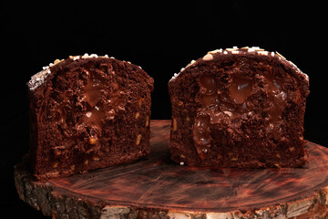 Panettone Cake, Kulich , Paska - dessert for Easter and Christmas. Panettone cut in half showing chocolate dough and chocolate filling on wooden board on black background