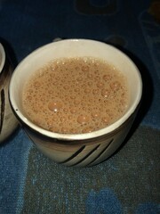  a cup of hot, frothy tea, likely a traditional Indian chai