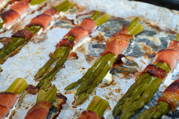 Delicious asparagus wrapped in crispy bacon on a baking sheet during a sunny afternoon barbecue...