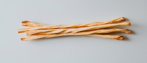 Group of long, thin, golden-brown breadsticks arranged in a horizontal line on a plain white background. the breadsticks appear to be freshly baked and have a crispy texture.