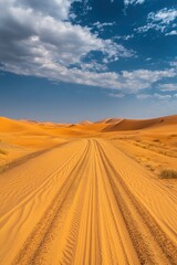 Fototapeta premium Serene desert landscape featuring tire tracks leading to distant dunes under a vast blue sky with clouds
