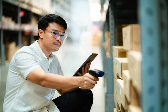 A man in a white shirt is using a barcode scanner to scan a product in a warehouse