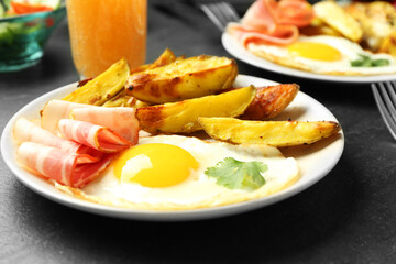 Tasty brunch. Fried egg, potato and bacon on dark textured table, closeup