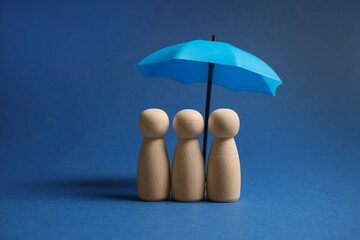 Human figures under umbrella on blue background. Insurance concept