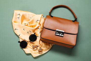 Beautiful scarf, sunglasses and handbag on teal background, flat lay