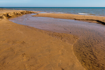 Runnoff water from the melting snow flows over the beach and cuts its way to Lake Michigan in early March at Harrington Beach State Park, Belgium, Wisconsin