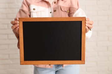 Woman holding blank small blackboard indoors, closeup