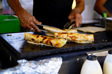 A chef in a food truck is making roti wrap with peanut butter.