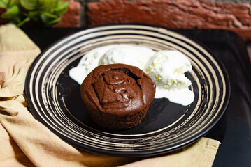 Molten Chocolate Cake with Ice Cream Dessert. Decadent molten chocolate cake served with melting vanilla ice cream scoops on a modern black striped plate.