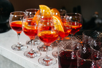 Glasses of red cocktails with orange slices.