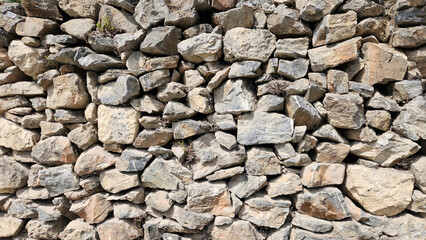 Wall made of black stones serves as the boundary of a rustic village house garden.