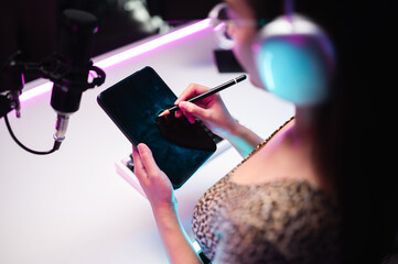Teenager girl hosts podcast in her room using LED lights, computer, headphones, condenser...