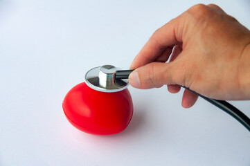 Top view of hand holding stethoscope and a red heart shaped with customizable space for text. Medical and health concept