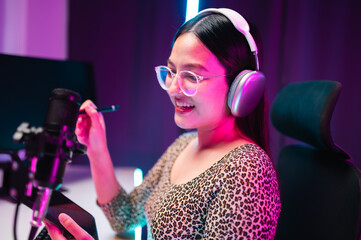 Teenager girl hosts podcast in her room using LED lights, computer, headphones, condenser...