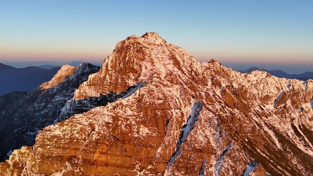 Aerial panorama of snow-covered Yushan bathed in sunset glow. The drone circles the majestic white peak, capturing its golden-lit slopes against the deepening twilight sky.