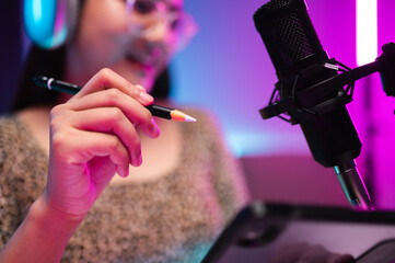 Teenager girl hosts podcast in her room using LED lights, computer, headphones, condenser...