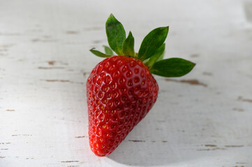 Freshly picked strawberry glistens under soft natural light on rustic wooden surface in a charming kitchen setting