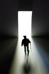 Obraz premium Elderly man walking away towards light through open door