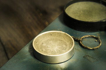 Old compass with magnifying glass on vintage book.