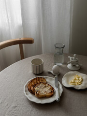A simple and delicious breakfast - toasts with butter, boiled egg, coffee on a round table