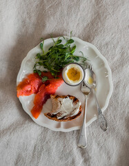 Delicious breakfast, brunch, snack - boiled egg, salted salmon, arugula, cream cheese bun sandwich on a gtay background, top view