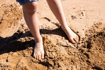 Toddler bare feet in the sand at a sunlit beach