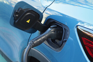 Electric car is plugged into a charging station. Close-up. 