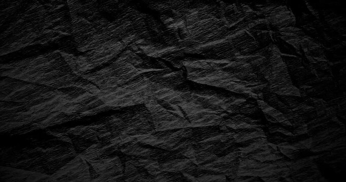 Dark crumpled texture in slow spin. Rough black surface rotates smoothly with gritty depth in gentle motion. Ideal for abstract ads in 4K.