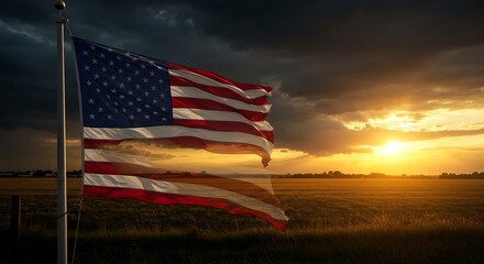 Obraz premium An American flag majestically waves at sunset, a symbol of freedom and patriotism against a dramatic sky, bathed in warm golden light.