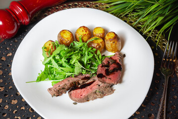 Grilled beef steak with roasted potatoes and arugula.