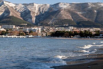 A beautiful mountain range with a city in the background. The city is full of buildings and the water is calm