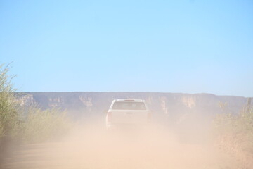 carro trafegando em estrada de terra levantando poeira