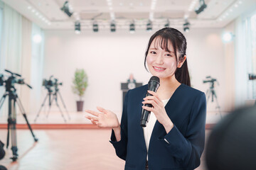 記者会見場からレポートをする女性のアナウンサー